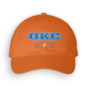 Könnte beinhalten: Orangefarbene Baseballkappe mit einem blauen und gelben gestickten Logo, auf dem "OKC" steht, darunter ein kleiner Kreis mit einem weißen "O".