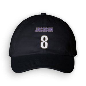 May include: Black baseball cap with a white number 8 and the name "JACKSON" in purple lettering.