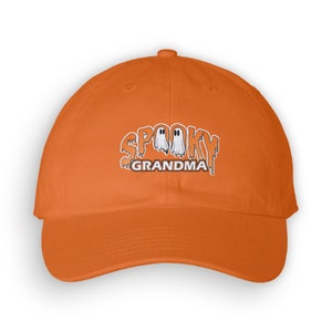 Op de afbeelding: Oranje baseballpet met een geborduurd ontwerp van geesten en de tekst "Spooky Grandma".