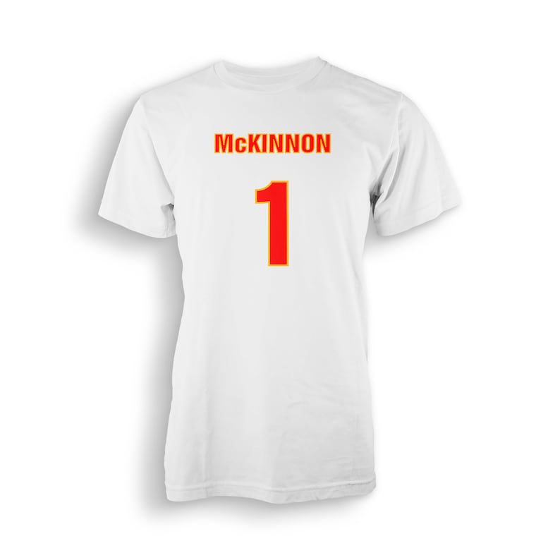 以下が含まれることがあります： 白地に「MCKINNON」という名前と「1」という数字が書かれたTシャツ。数字は赤色で、黄色い縁取りがされている。