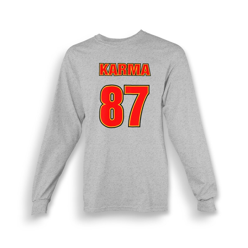 Op de afbeelding: Grijs longsleeve shirt met de tekst "KARMA" en het nummer "87" gedrukt op de achterkant in rood met een gele omtrek.
