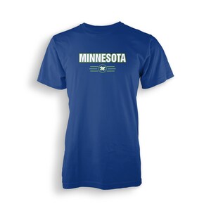 Könnte beinhalten: Ein königsblaues T-Shirt mit einer weißen Grafik des Wortes "MINNESOTA" mit grünem Umriss und einem grün-weißen "M"-Logo darunter.