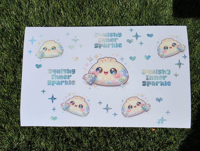 May include: A white sticker sheet featuring multiple illustrations of a smiling, round dumpling character with large, sparkling eyes. Each character holds a diamond. The text "Squishy Inner Sparkle" appears in a blue, glittery font alongside small stars and hearts.