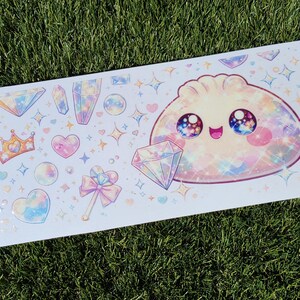 May include: A rectangular sticker sheet featuring a large, smiling, iridescent dumpling character with galaxy-filled eyes, surrounded by various pastel-colored illustrations including diamonds, crystals, a crown, hearts, and a magical wand.