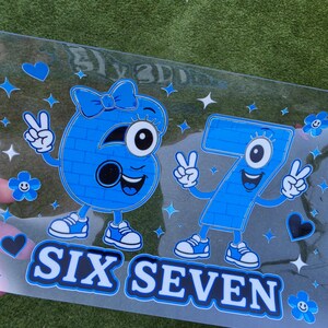 May include: A clear decal featuring a blue cartoon number six with a bow and a blue cartoon number seven, both with arms, legs, and sneakers making peace signs. The design includes blue hearts, flowers, and stars with the text SIX SEVEN below.
