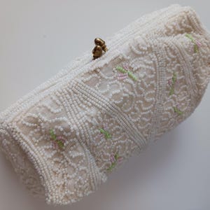 Cartera de mano con cuentas blancas y bordado con un elegante estampado de flores