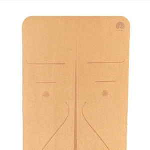 May include: A brown cork yoga mat with a VAMU logo in the top right corner. The mat has a textured surface and a design of lines and shapes.