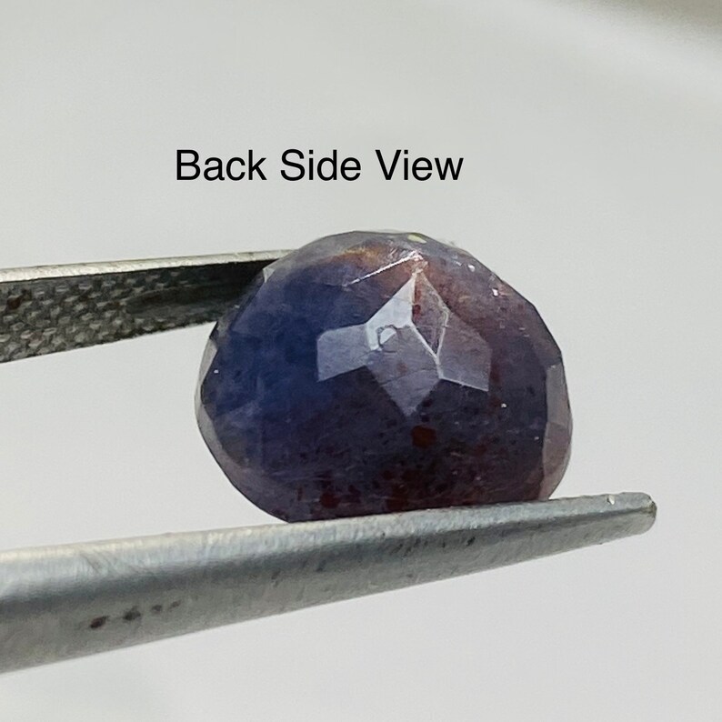 Pu&ograve; includere: Vista posteriore di una pietra preziosa viola con taglio sfaccettato. La pietra preziosa &egrave; tenuta da una pinzetta.