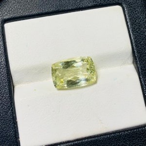 May include: A light green gemstone with a rectangular shape, displayed on a white background.