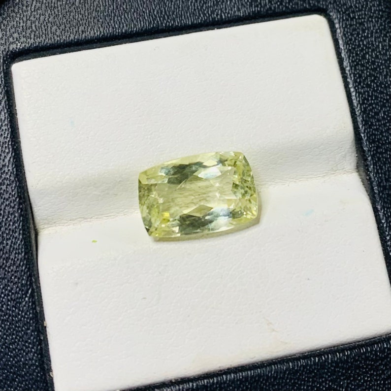 May include: A light green gemstone with a rectangular shape, displayed on a white background.