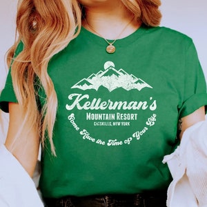 May include: Green t-shirt featuring the text "Kellerman's Mountain Resort Catskills, New York" with a mountain graphic. The shirt has a crew neck and short sleeves. The text "Come Have the Time of Your Life" is printed around the graphic.