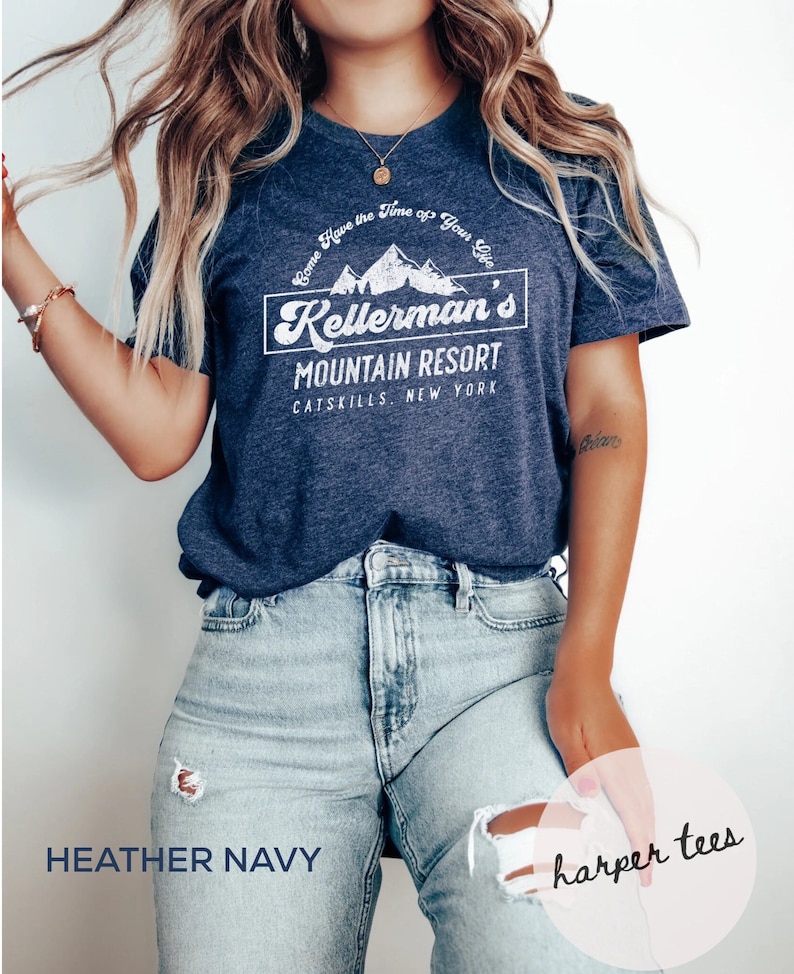 Op de afbeelding: Heather navyblauw t-shirt met een witte afbeelding van bergen en de tekst "Come Have the Time of Your Life Kellerman's Mountain Resort Catskills, New York".