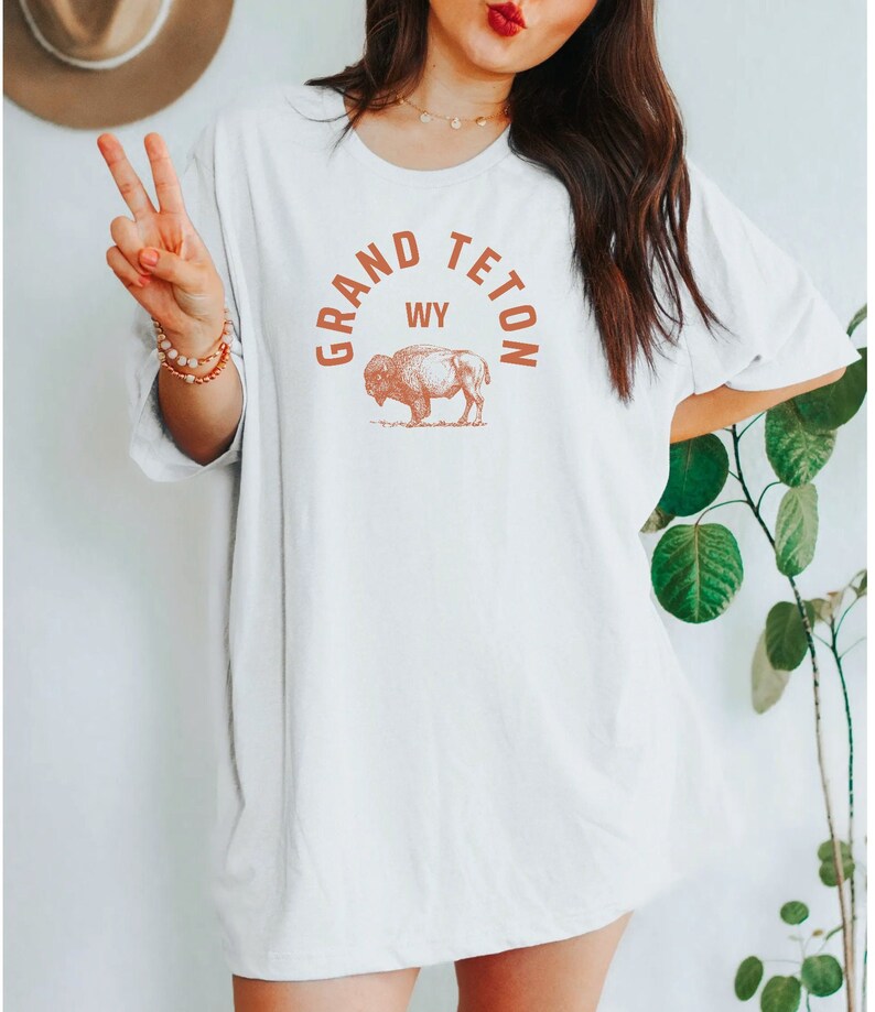 May include: White oversized t-shirt with a brown graphic of a buffalo and the text "GRAND TETON WY" in a circle.