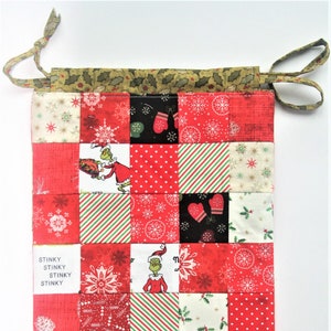 May include: A red and green patchwork fabric gift bag with a drawstring closure. The bag features a Grinch character and the text "Stinky Stinky Stinky Stinky" and "know me is to love BOO HOO".
