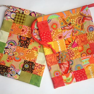 May include: Two colorful patchwork fabric drawstring bags with a variety of floral and geometric patterns in shades of orange, red, green, brown, and yellow.