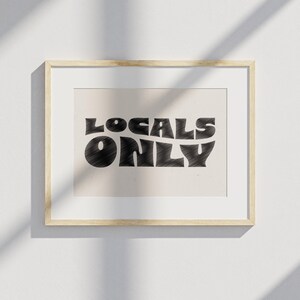 May include: A framed print with the text "LOCALS ONLY" in a retro, wavy font. The text is in black on a light beige background.