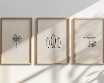 May include: Three framed prints with a beach theme. The first print features a palm tree, the second print features three surfboards, and the third print features a beach umbrella and a lounge chair.