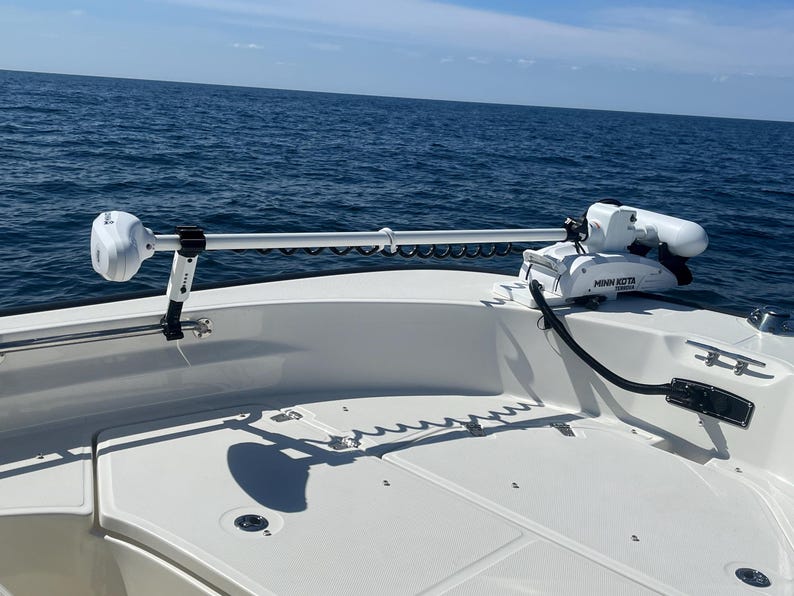 Puede incluir: Un motor de pesca el&eacute;ctrico Minn Kota blanco montado en la parte trasera de un barco. El motor est&aacute; extendido y el barco est&aacute; en el agua.