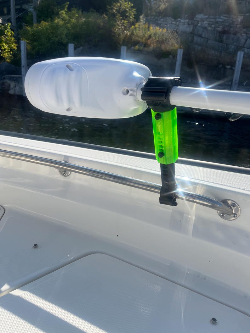 Puede incluir: Un motor de barco blanco con un soporte verde y negro. El motor est&aacute; unido a un barco blanco.