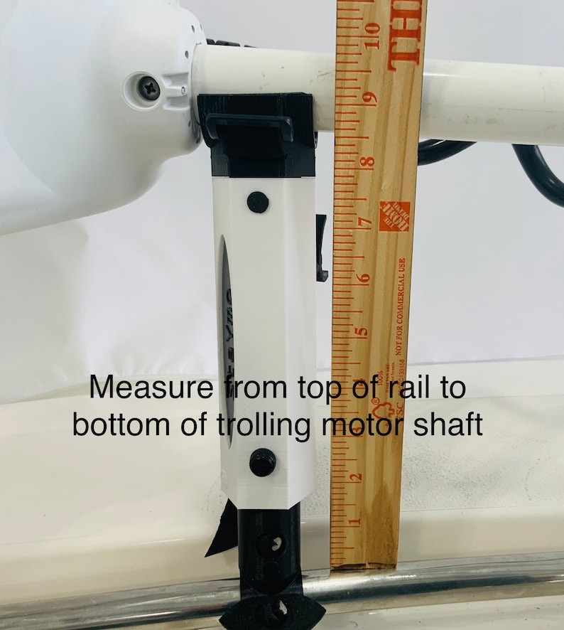 Puede incluir: Un soporte de motor de pesca de arrastre blanco con un soporte negro y una regla que mide 17,8 cm. El texto "Measure from top of rail to bottom of trolling motor shaft" es visible en la imagen.