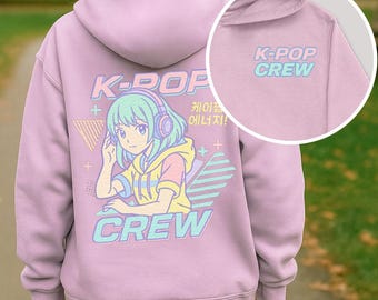May include: A lilac hoodie featuring a K-POP graphic. The design includes an anime-style character with headphones, the words "K-POP CREW," and Korean text. The hoodie has a drawstring hood and a kangaroo pocket.