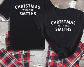 May include: Matching black pyjamas with red and black checked trousers and a black t-shirt with the text "Christmas with the Smiths" in white.