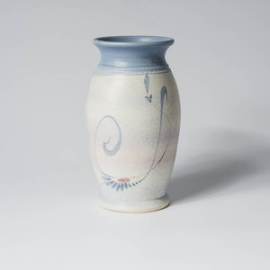 May include: A light blue ceramic vase with a white glaze and a hand-painted design in shades of blue and pink.