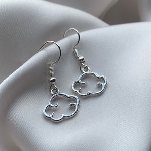 May include: A pair of silver cloud-shaped earrings with a simple design. The earrings are hanging from silver hooks.