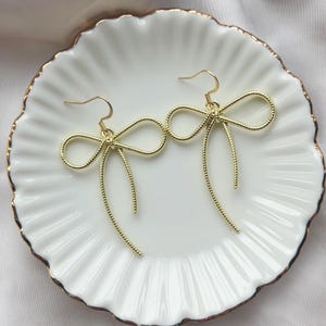 Orecchini pendenti con fiocco in nastro dorato, gioielli lunghi e vistosi, regalo elegante e civettuolo