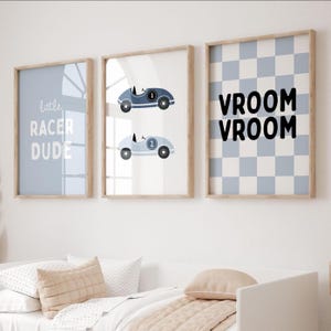 Puede incluir: Tres impresiones enmarcadas con temática de carreras. Una impresión dice "little RACER DUDE" en blanco sobre un fondo azul claro. La segunda impresión muestra dos coches de carreras. La tercera impresión tiene un patrón de cuadros azules y blancos con las palabras "VROOM VROOM".