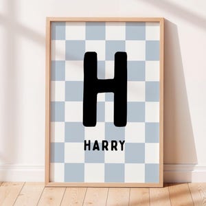 Peut inclure: Une affiche encadrée avec la lettre "H" noire en grand, surmontant le nom "HARRY". Le fond est un motif à carreaux bleu clair et blanc. Le cadre est en bois clair.