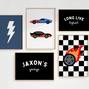 Puede incluir: Un conjunto de cinco láminas enmarcadas que incluyen un rayo blanco sobre azul, dos coches de carreras con llamas sobre blanco, el texto LONG LIVE boyhood sobre negro, JAXON'S garage sobre negro y un neumático en llamas sobre un fondo de cuadros.