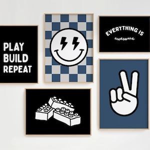 May include: Five framed art prints with a playful theme. The prints feature bold graphics and text, including a smiley face with lightning bolts, a peace sign, and the words "PLAY BUILD REPEAT" and "Everything is awesome."