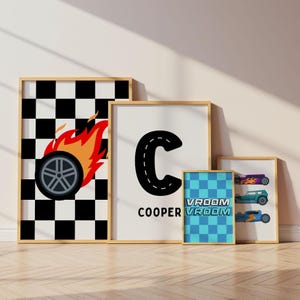 May include: Four framed wall art prints featuring racing themes. One print shows a black and white checkered pattern with a flaming tire. Another displays a large letter C styled like a road with the name COOPER. A blue checkered print says VROOM VROOM, and a final print shows three colorful race cars.