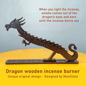 Könnte beinhalten: Ein hölzerner Drachen-Räucherstäbchenhalter mit einzigartigem Design. Der Drache ist braun mit gelben Akzenten und hat einen langen Körper mit einem gebogenen Schwanz. Der Text lautet: „Wenn Sie das Räucherstäbchen anzünden, kommt Rauch aus den Augen und Ohren des Drachen.“