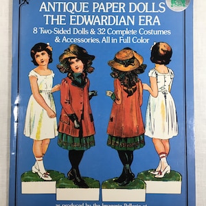 May include: A book cover featuring antique paper dolls from the Edwardian era. The cover shows four dolls in full color, with the text "Antique Paper Dolls The Edwardian Era 8 Two-Sided Dolls & 32 Complete Costumes & Accessories, All in Full Color as produced by the Imagerie Pellerin at EPINAL."