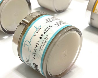 May include: A close-up of a white jar with a silver lid. The jar is labeled "Island Breeze Shea Butter 4 fl. oz/118 mL" and "Diamonds Body Care".