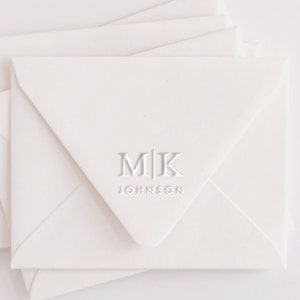 May include: White envelopes with a monogrammed design. The monogram is "M|K" with the text "JOHNSON" below it.