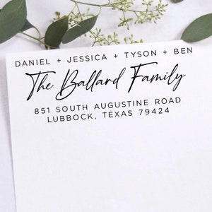 May include: A white card with the names Daniel, Jessica, Tyson, and Ben, and the words "The Ballard Family" in elegant script. The address 851 South Augustine Road, Lubbock, Texas 79424 is printed below. Greenery is in the background.