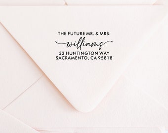 May include: Close-up of a white envelope with the text "THE FUTURE MR. & MRS. williams" in black script. Below the name is the address: 32 HUNTINGTON WAY, SACRAMENTO, CA 95818. The envelope is on a light pink background.