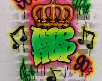 May include: A green and yellow graffiti design of the word "Hip Hop" with a gold crown above it. The design is surrounded by dollar signs, musical notes, and the text "90's" in yellow.