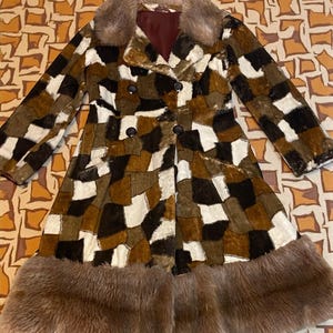 May include: A vintage patchwork coat in shades of brown, white, and black. The coat features a faux fur collar and trim, with a double-breasted button closure. The coat has long sleeves and a knee-length design, perfect for a retro look.