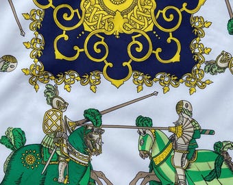 May include: White fabric featuring a navy blue and gold decorative pattern. Two knights in green and white armour on horseback are jousting. The design includes repeating patterns of spears and tassels.