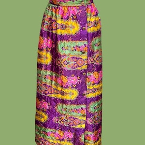 Peut inclure: Jupe longue matelassée à boutons, ornée d'un motif floral éclatant. La jupe présente une taille haute et une coupe droite. La palette de couleurs comprend le violet, le jaune, le rose et le vert. Une pièce vintage audacieuse.