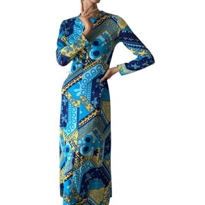 Puede incluir: Un vestido largo de manga larga con un patrón geométrico en tonos azules, amarillos y blancos. El vestido tiene un escote redondo y mangas largas.