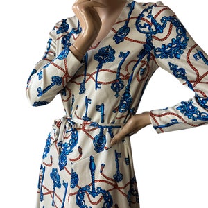 May include: A long-sleeved wrap dress with a V-neckline. The dress is made of a white fabric with a pattern of blue keys and red rope.