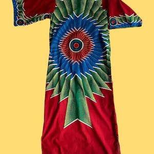 May include: A red, blue and green patterned dress with a long, flowing skirt and short sleeves. The dress features a large, circular design in the centre.