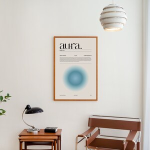 May include: A framed poster with the word "aura" in black text on a light beige background. The poster features a blue circle with a gradient effect and text about the color blue. The poster is hanging on a white wall.