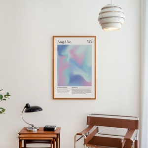 May include: A framed poster with a light blue, pink, and purple abstract design. The poster has the text "Angel No. 555" at the top. The poster is hanging on a white wall in a room with a brown leather chair, a small table, and a lamp.