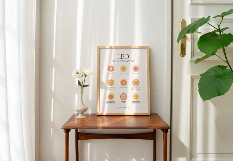 May include: A framed print with a light pink background and the text "LEO DAILY AFFIRMATIONS" in black. The print features 12 colorful circles with affirmations for the zodiac sign Leo.